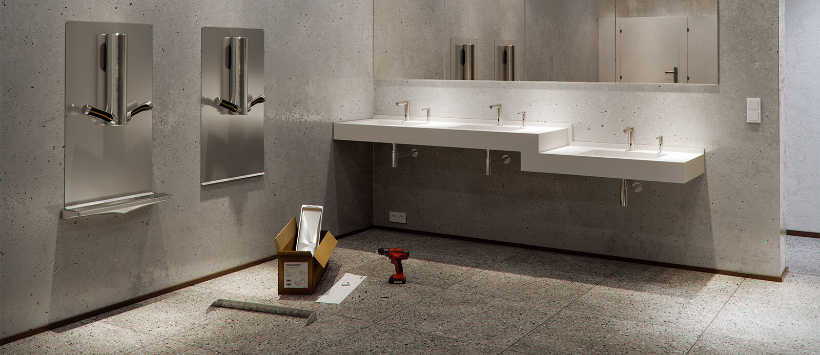 A bathroom made out of stone, with 2 Dyson Airblade Hand Dryers hanging on the wall next to each other and a drilling machine with some spare parts in a cardboard box standing in front of it on the ground.